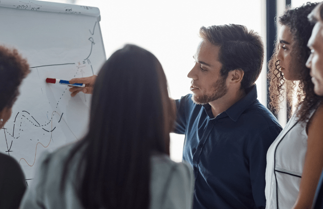 Team of professionals reviewing AI-related data and analytics on a whiteboard during a strategy meeting