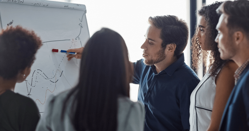 Team of professionals reviewing AI-related data and analytics on a whiteboard during a strategy meeting